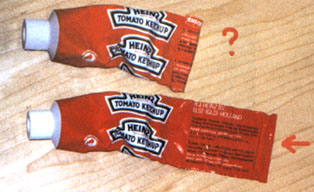 Afbeelding van tube's tomatenketchup, halfleeg, met gestanste houdbaarheidsdatum op de felsrand.